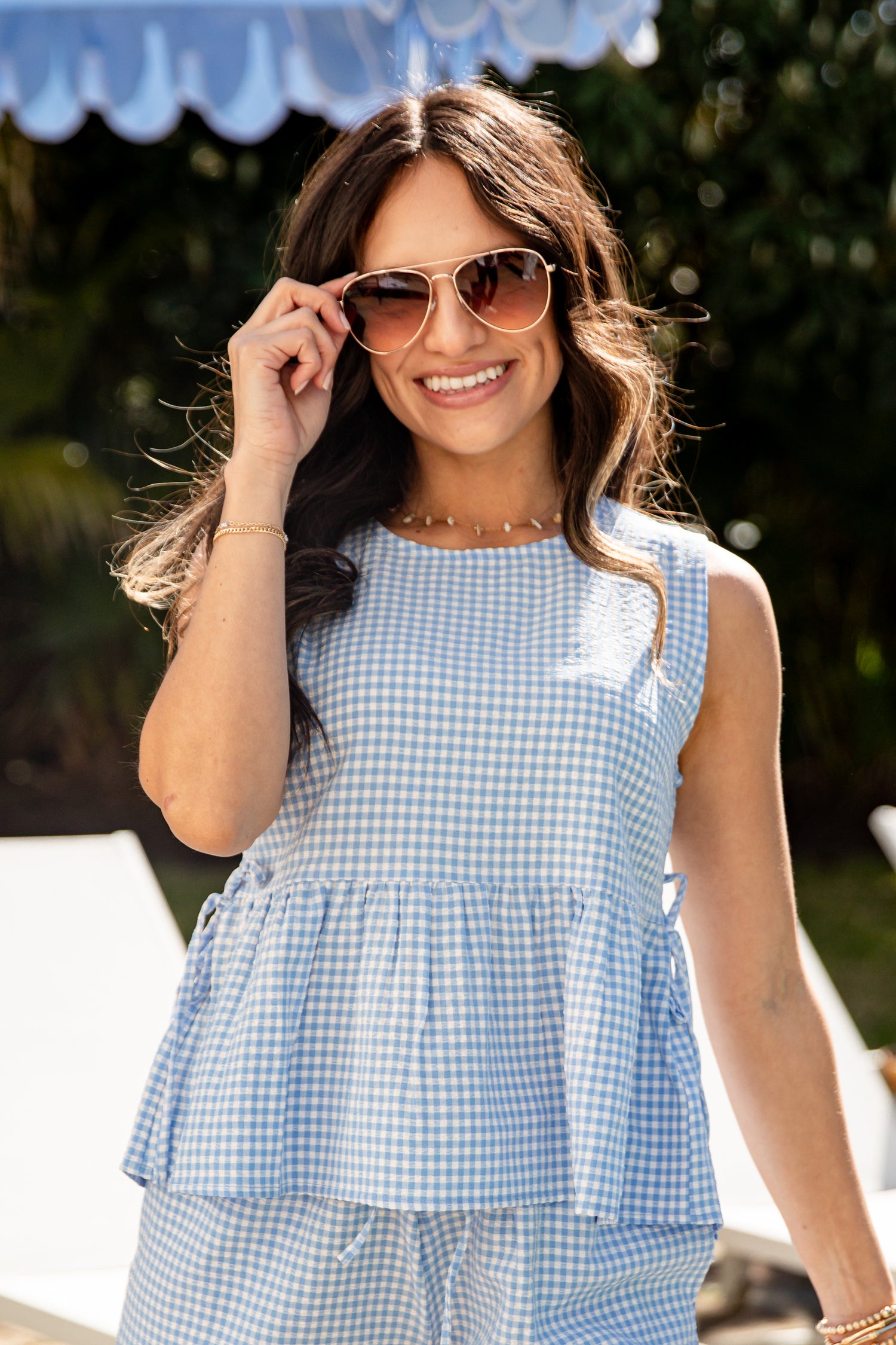 Woman wearing a blue checkered dress and sunglasses outdoors