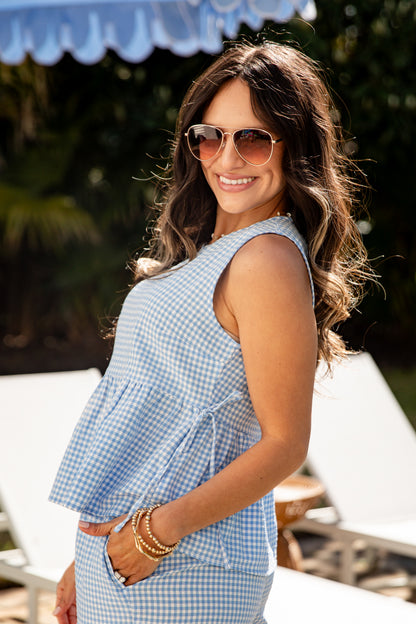 Woman wearing a blue checkered dress and sunglasses outdoors