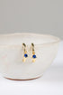 Gold earrings with blue gemstones on a white surface