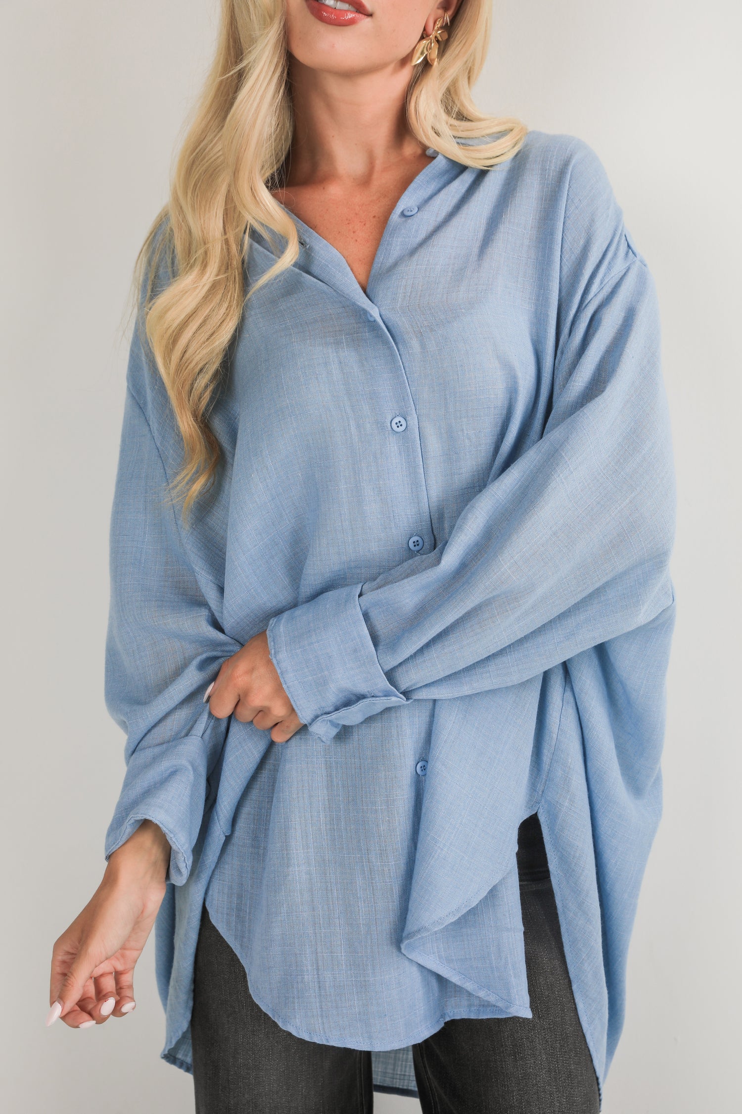 Woman wearing a light blue button-up shirt against a plain background