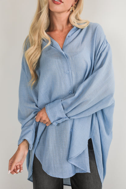 Woman wearing a light blue button-up shirt against a plain background