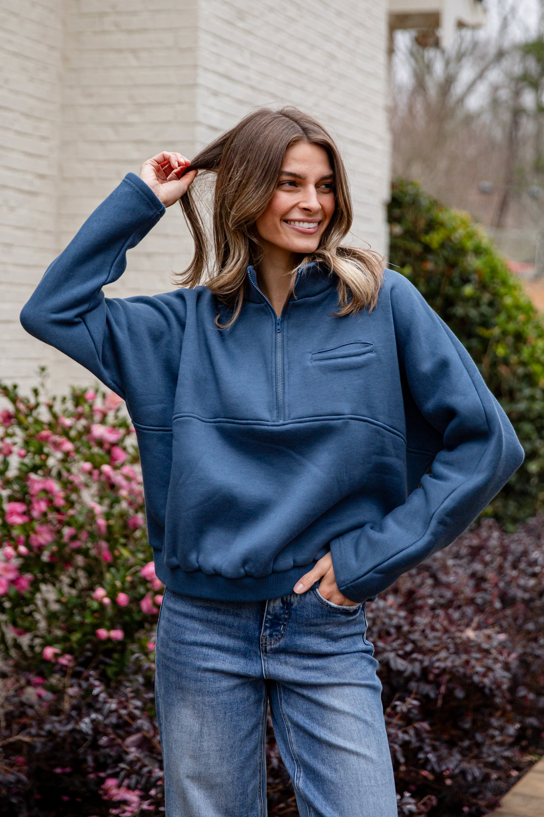 Woman wearing a blue pullover with a half-zip design outdoors.