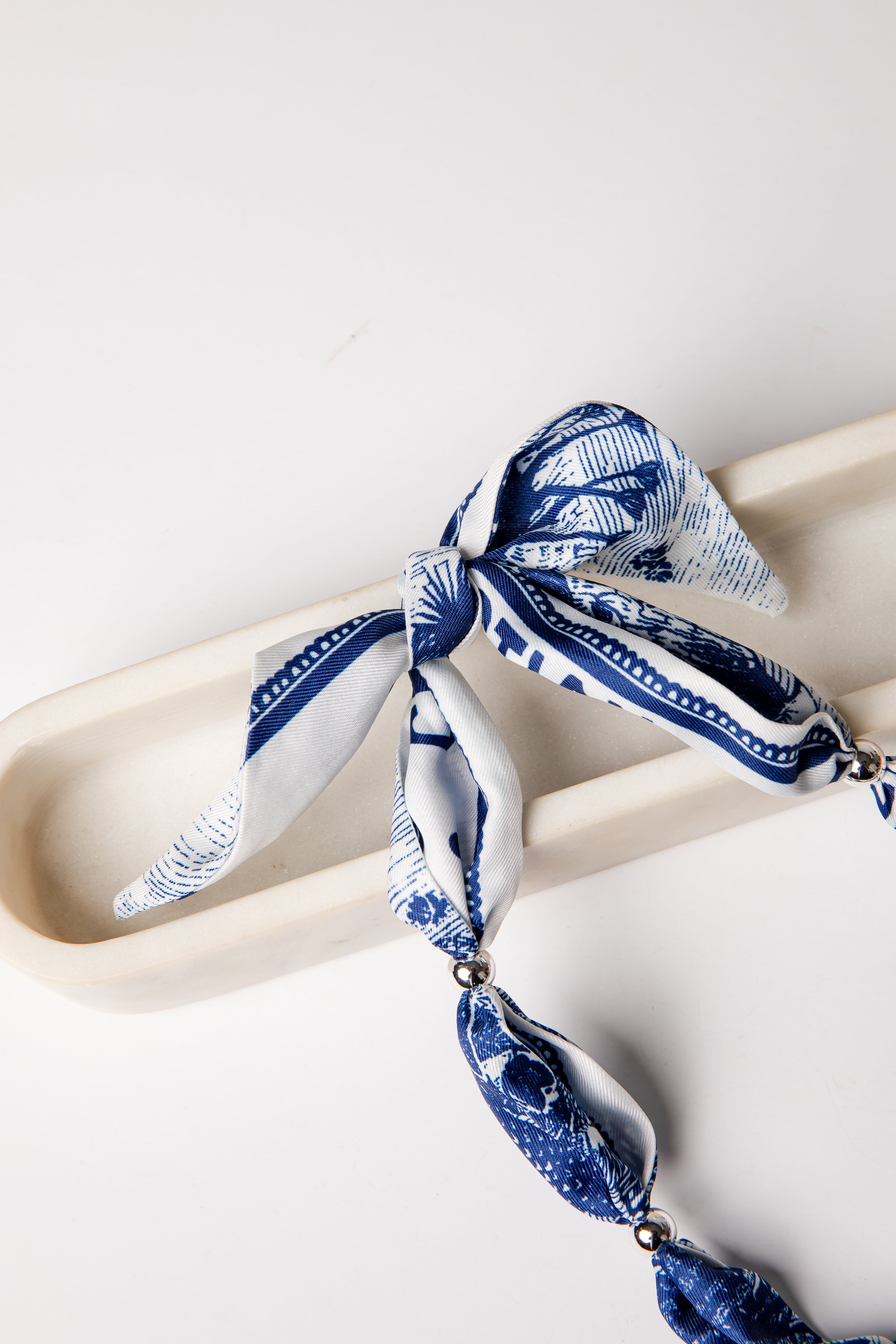 Blue and white patterned scarf tied on a white surface