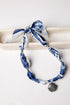 Blue and white patterned scarf with shell charm on a white background