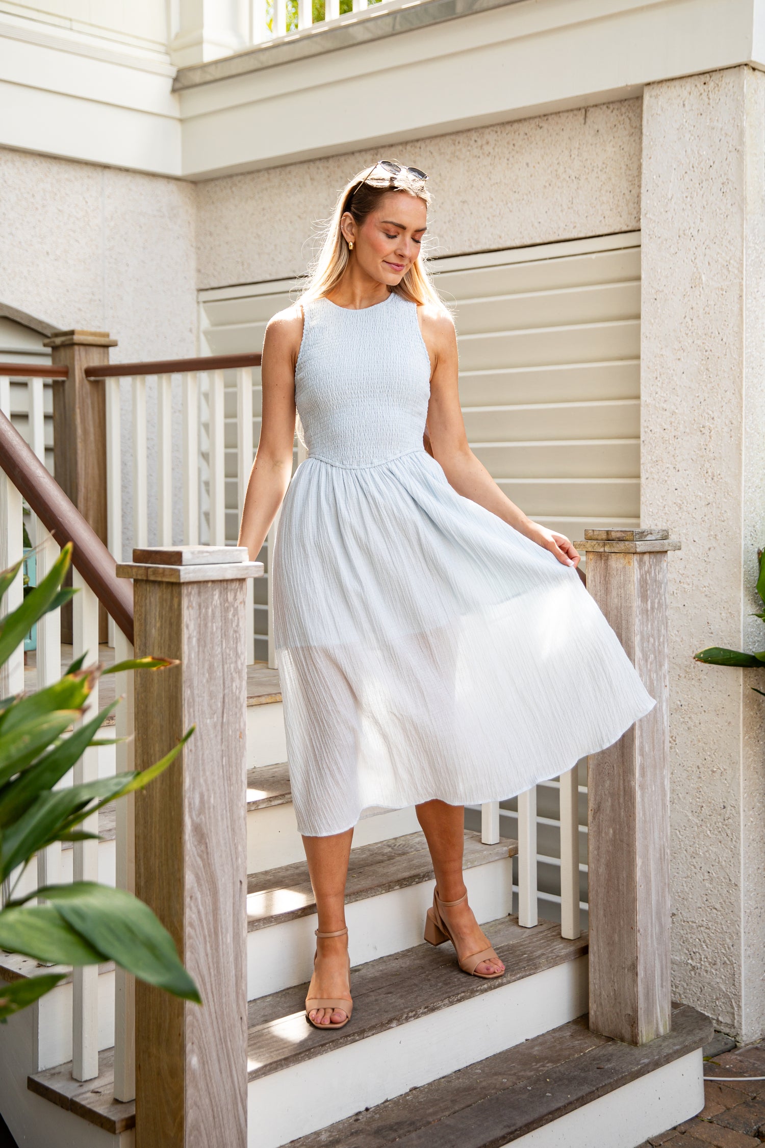 Woman in a light blue dress standing on a staircase