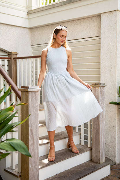 Woman in a light blue dress standing on a staircase