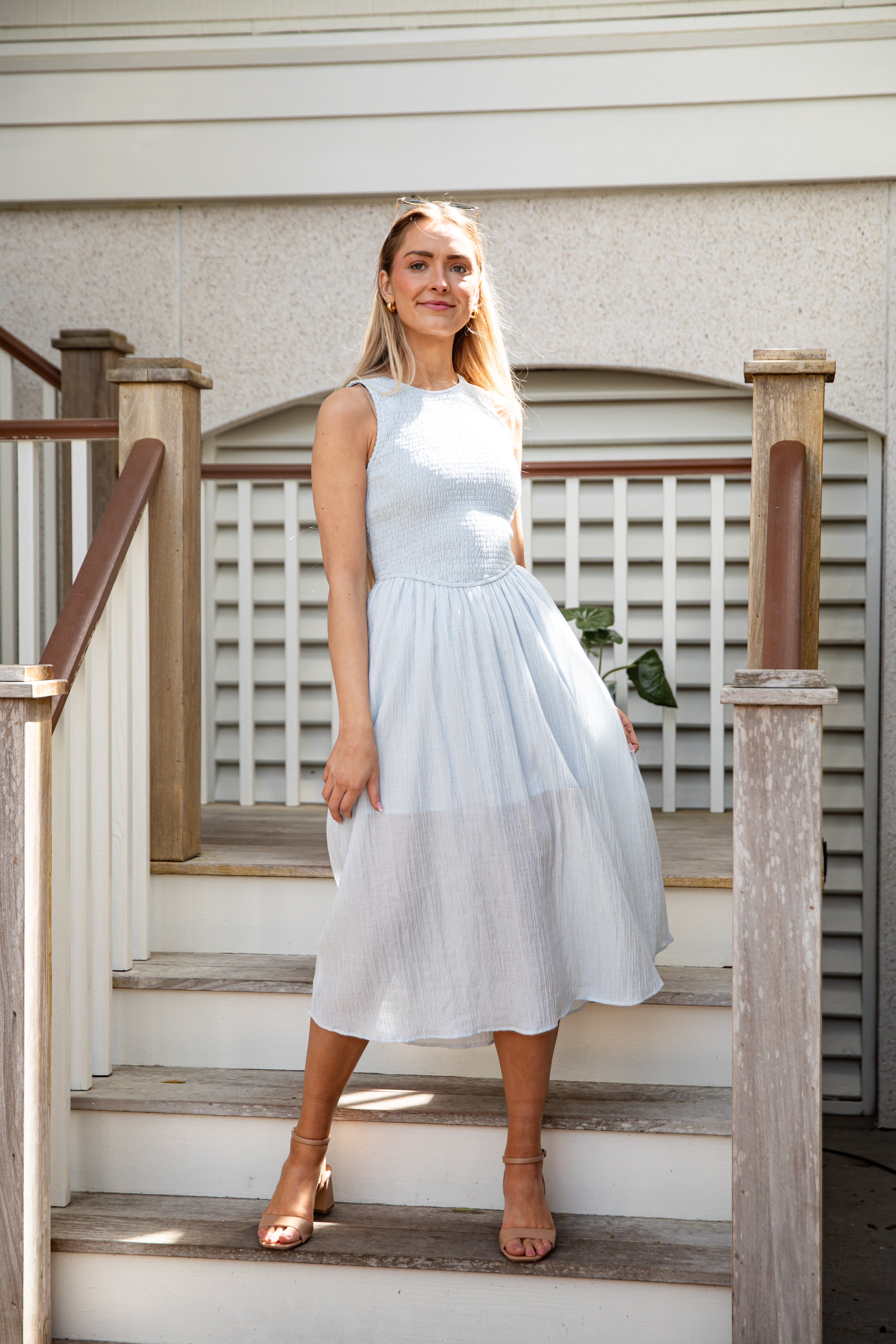Woman in a white dress standing on wooden steps outdoors