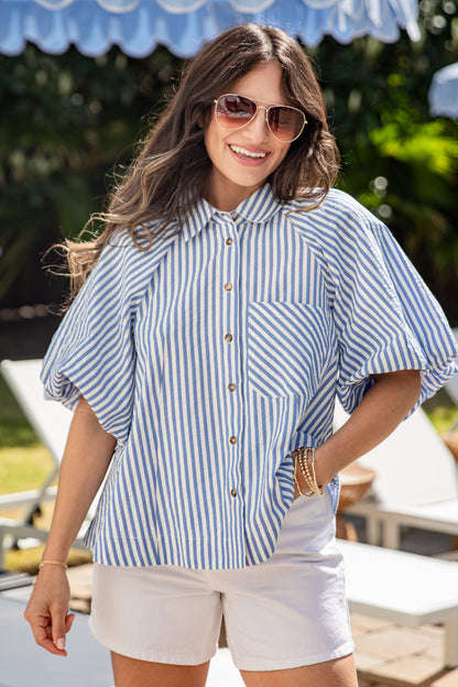Woman wearing a blue and white striped shirt and sunglasses outdoors.