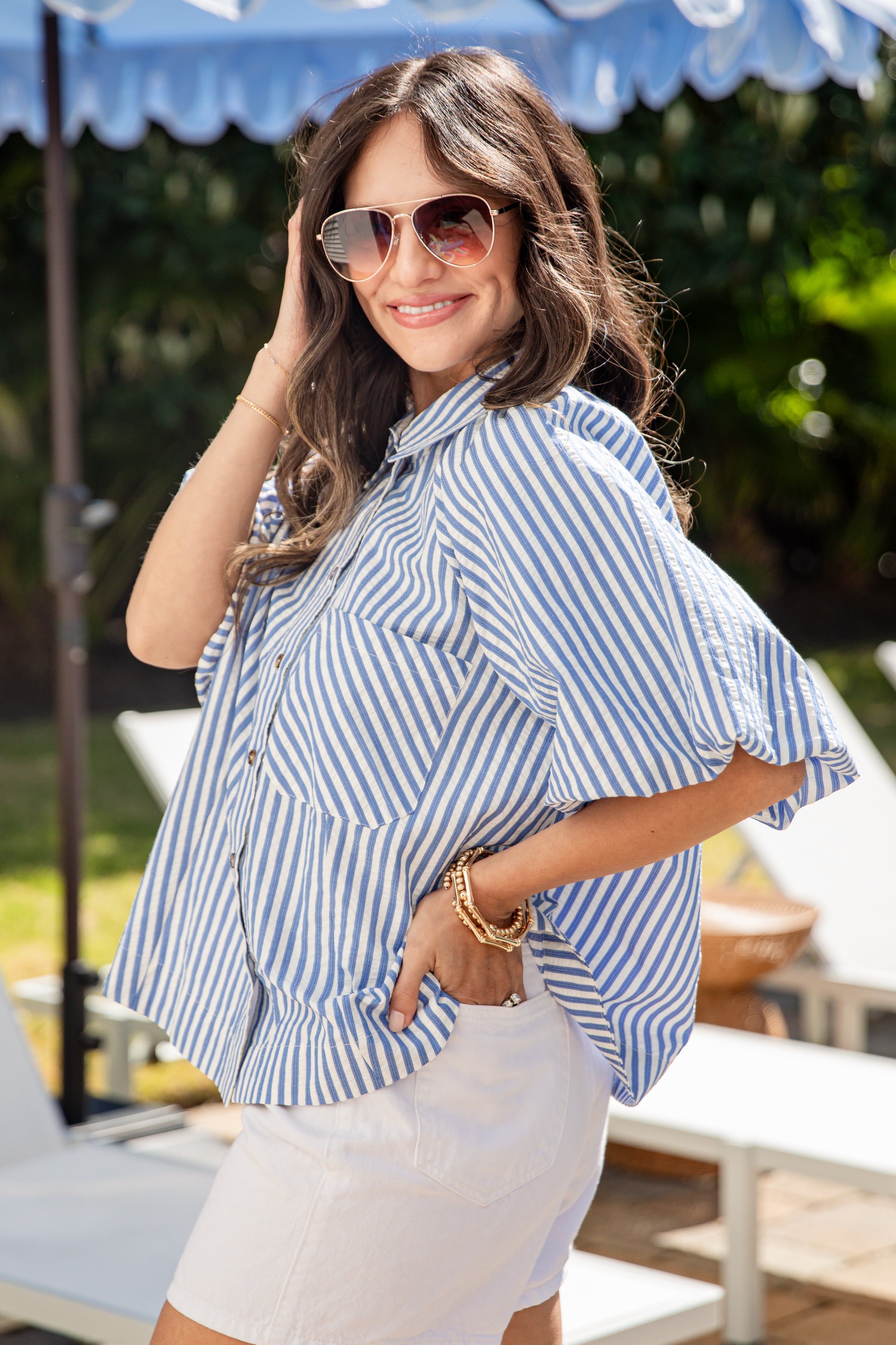 Woman wearing a blue and white striped shirt and sunglasses outdoors.