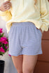 Person wearing a yellow sweatshirt and blue and white striped shorts with a blurred background