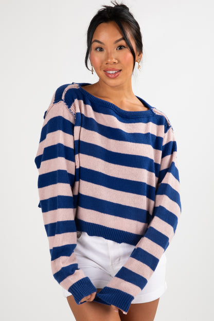 Woman wearing a blue and pink striped sweater on a white background
