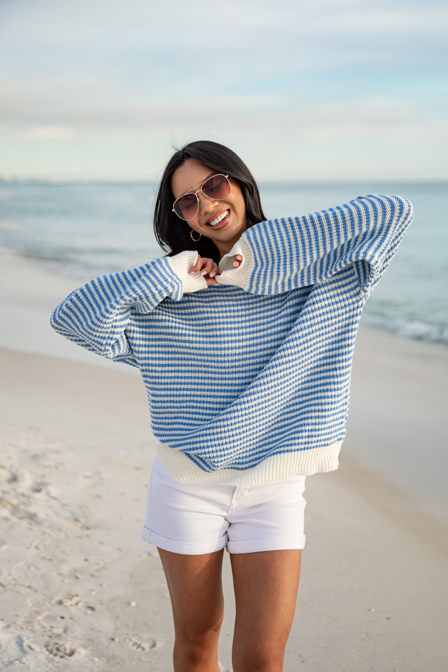 Woman wearing a blue and white checkered sweater on a beach