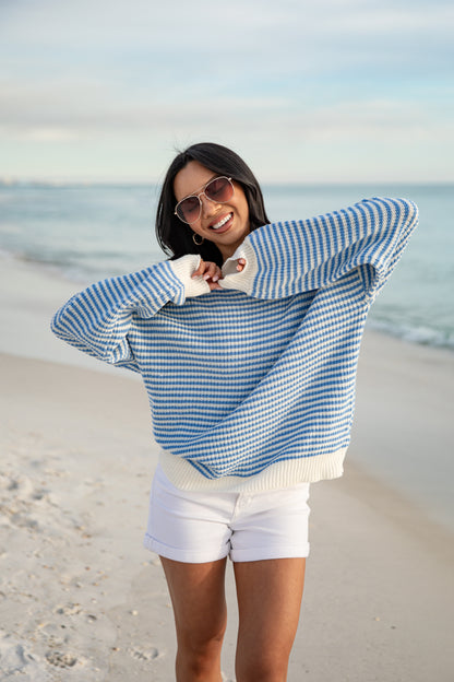Woman wearing a blue and white checkered sweater on a beach