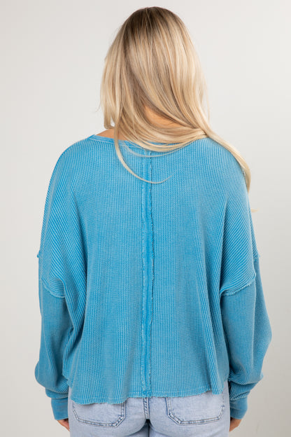 Person wearing a blue sweater from behind on a plain background