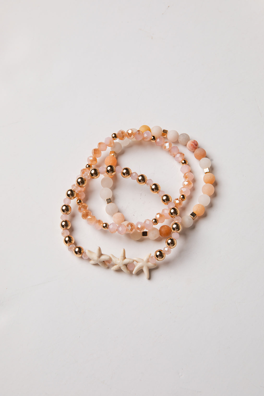 Set of beaded bracelets with starfish charm on a light gray background