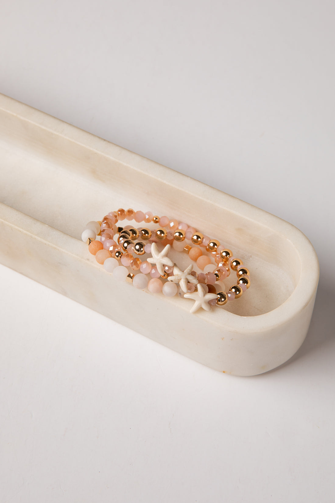 Bracelet with starfish and beads on a white dish