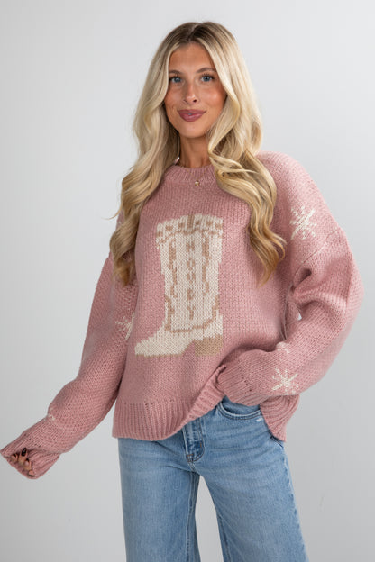 Woman wearing a pink sweater with a design on a plain background