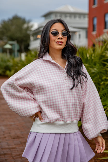 Woman wearing a pink checkered shirt and purple skirt outdoors.