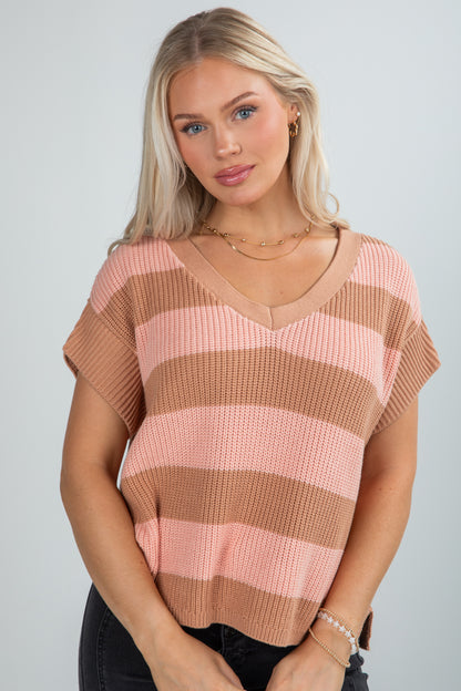 Woman wearing a pink and brown striped sweater against a plain background