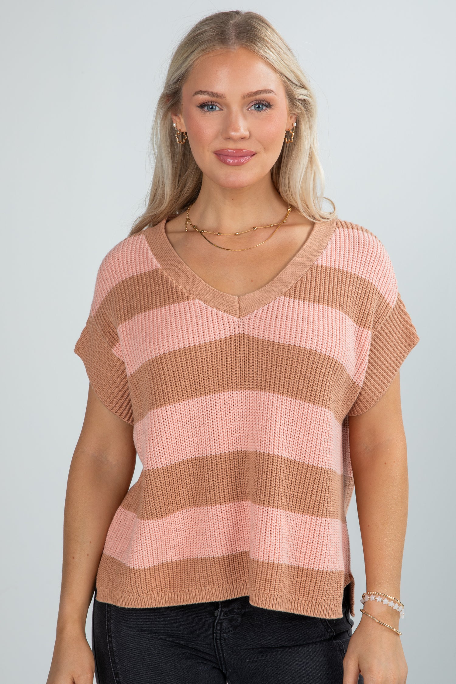 Woman wearing a pink and brown striped sweater against a plain background