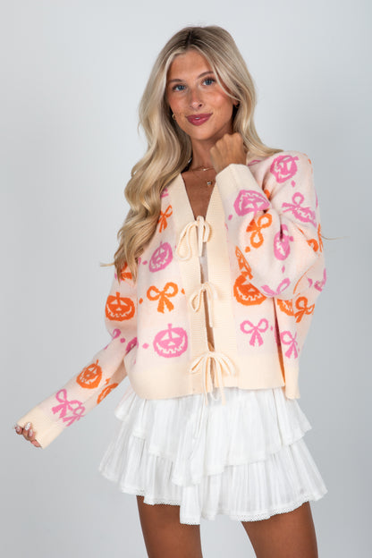 Woman wearing a colorful cardigan with pumpkins and bows on a plain background