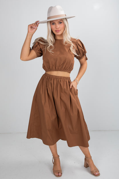 Woman wearing a brown outfit with a hat on a white background