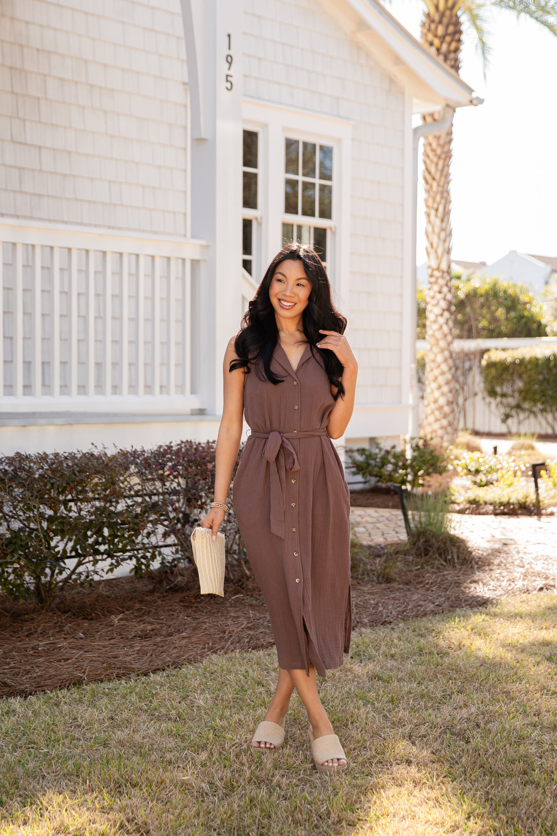Woman in a brown dress standing in front of a house
