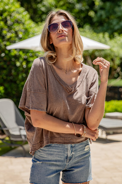 Woman wearing a brown oversized shirt and denim shorts outdoors.