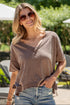 Woman wearing a brown oversized shirt and denim shorts outdoors.