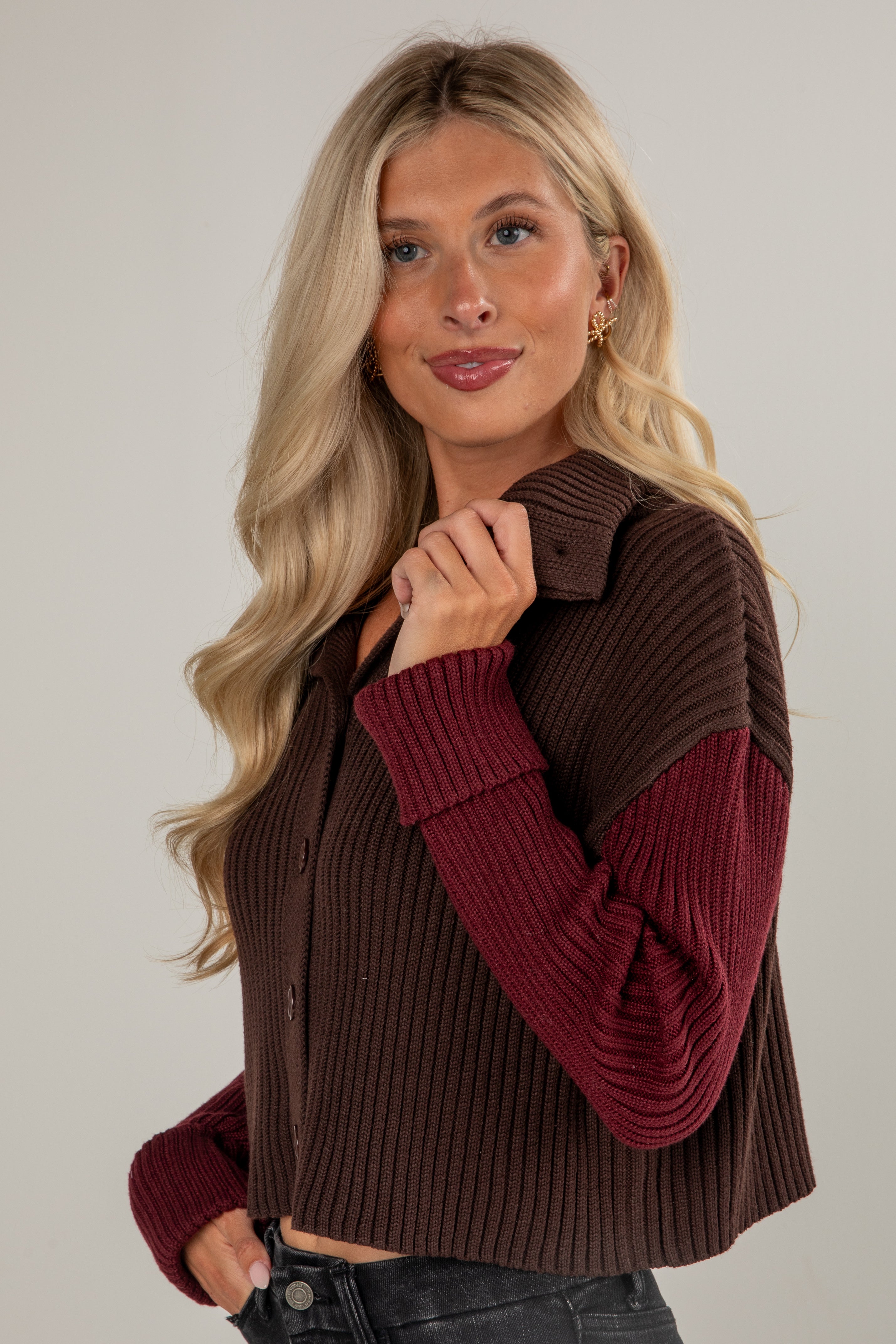 Woman wearing a brown and burgundy sweater vest against a plain background