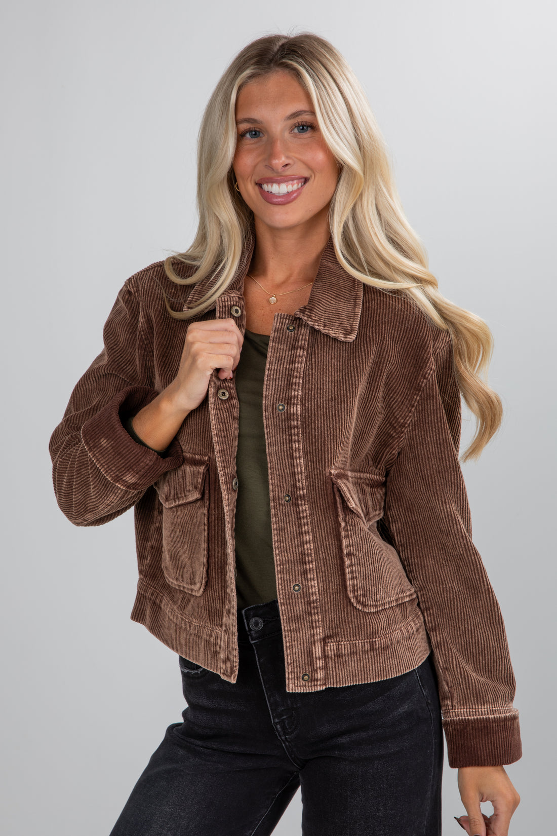 Woman wearing a brown corduroy jacket on a plain background