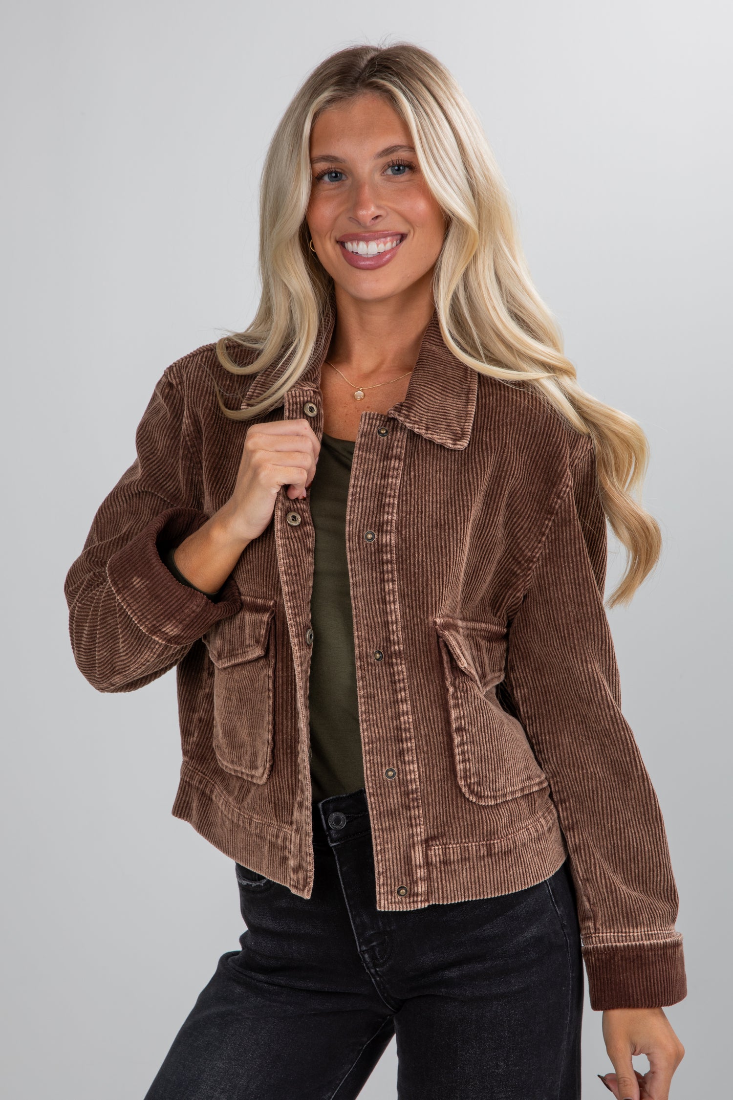 Woman wearing a brown corduroy jacket on a plain background