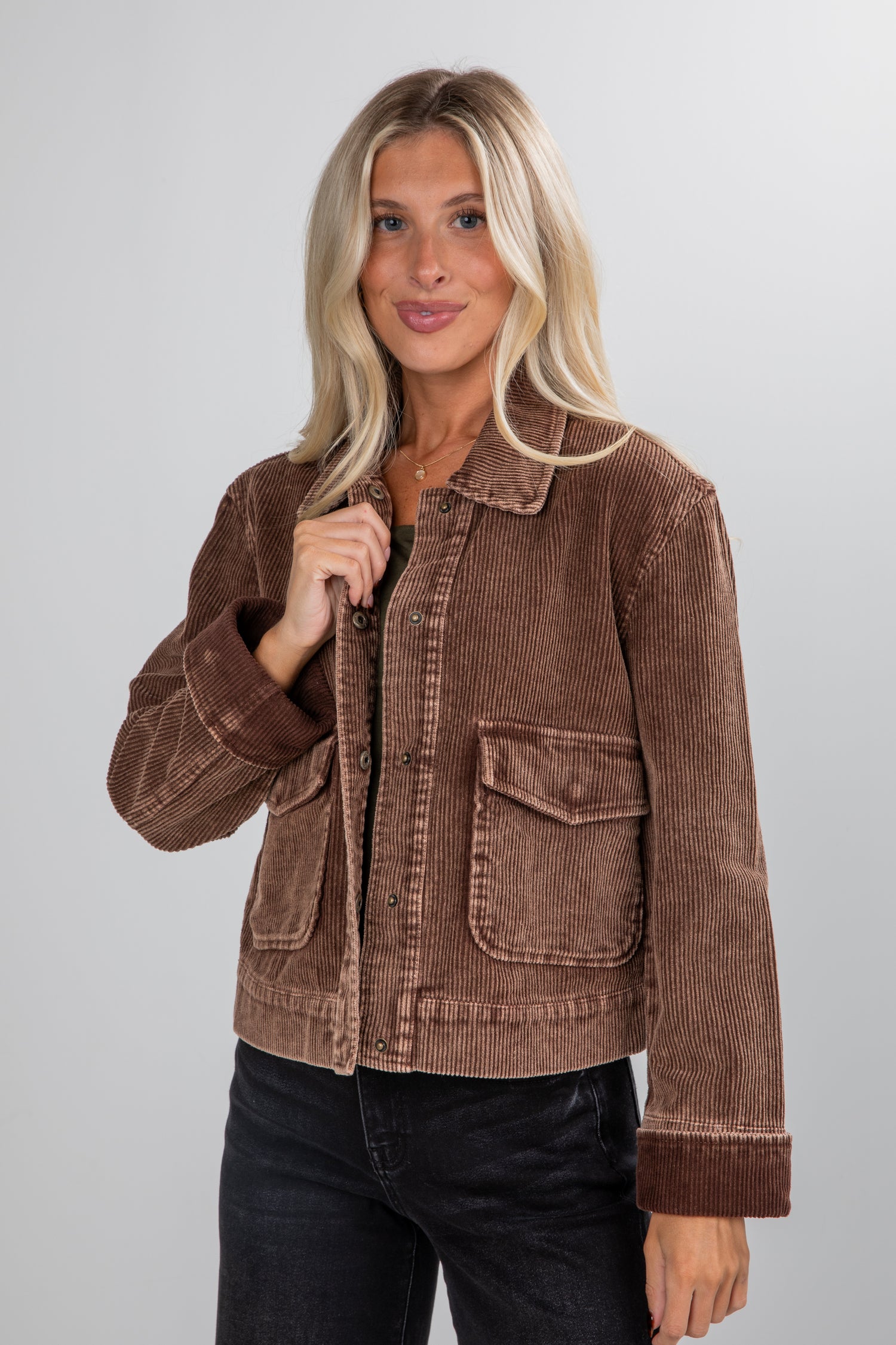 Woman wearing a brown corduroy jacket against a plain background