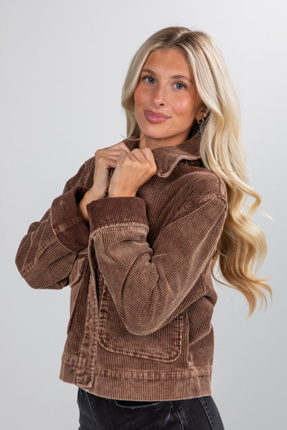 Woman wearing a brown corduroy jacket against a plain background