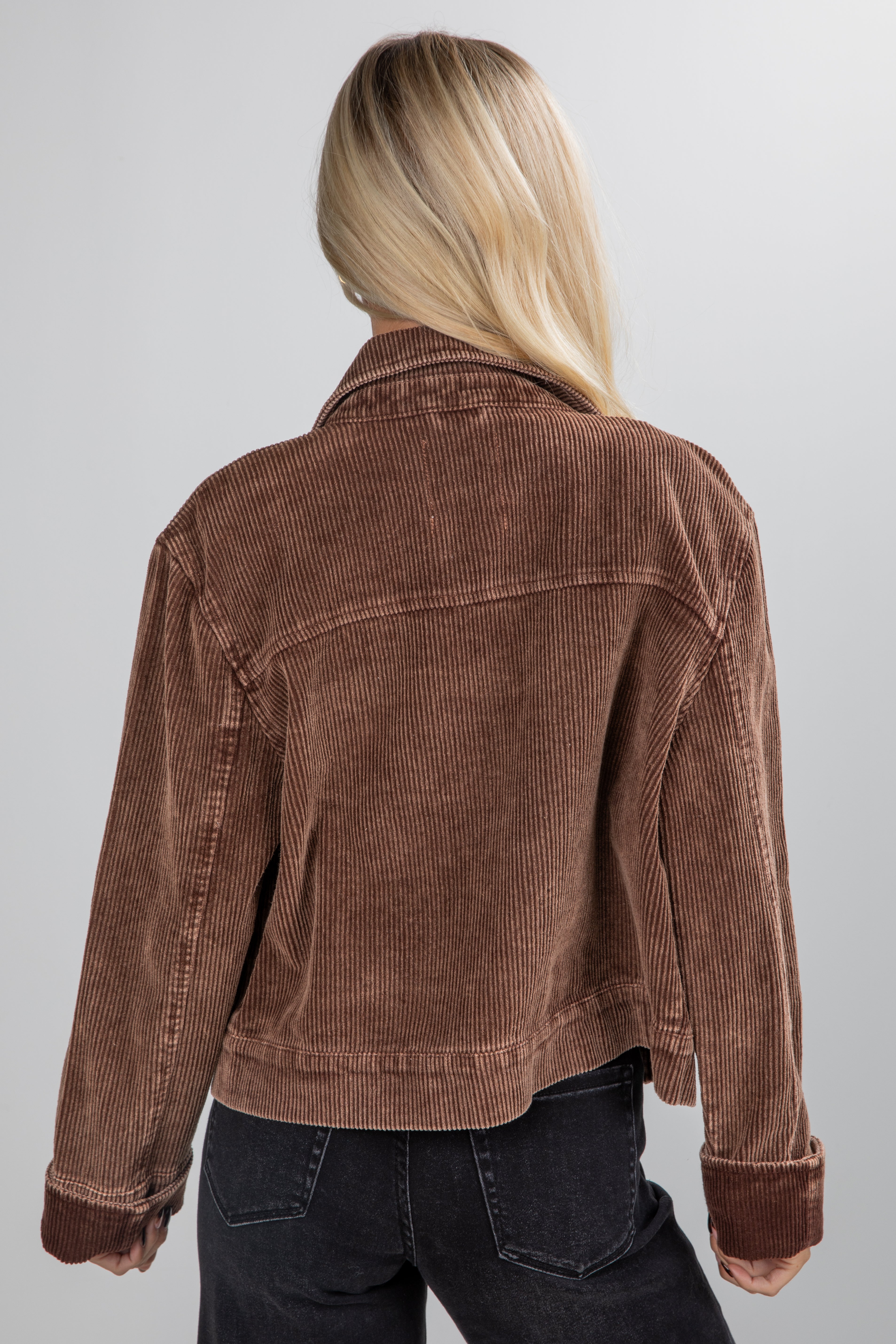 Person wearing a brown corduroy jacket on a plain background