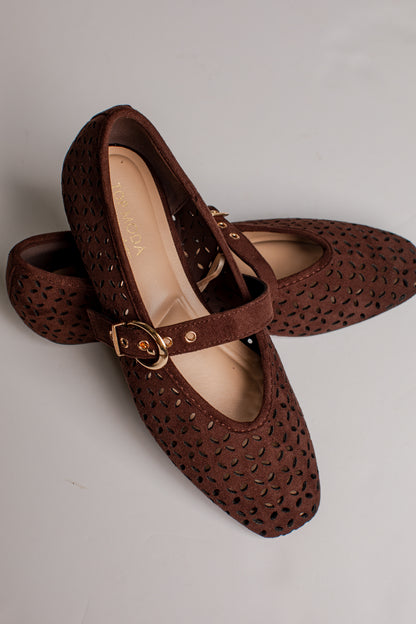 A pair of dark brown Mary Jane shoes with a textured, perforated upper and a gold-tone buckle strap, displayed on a light gray background.
