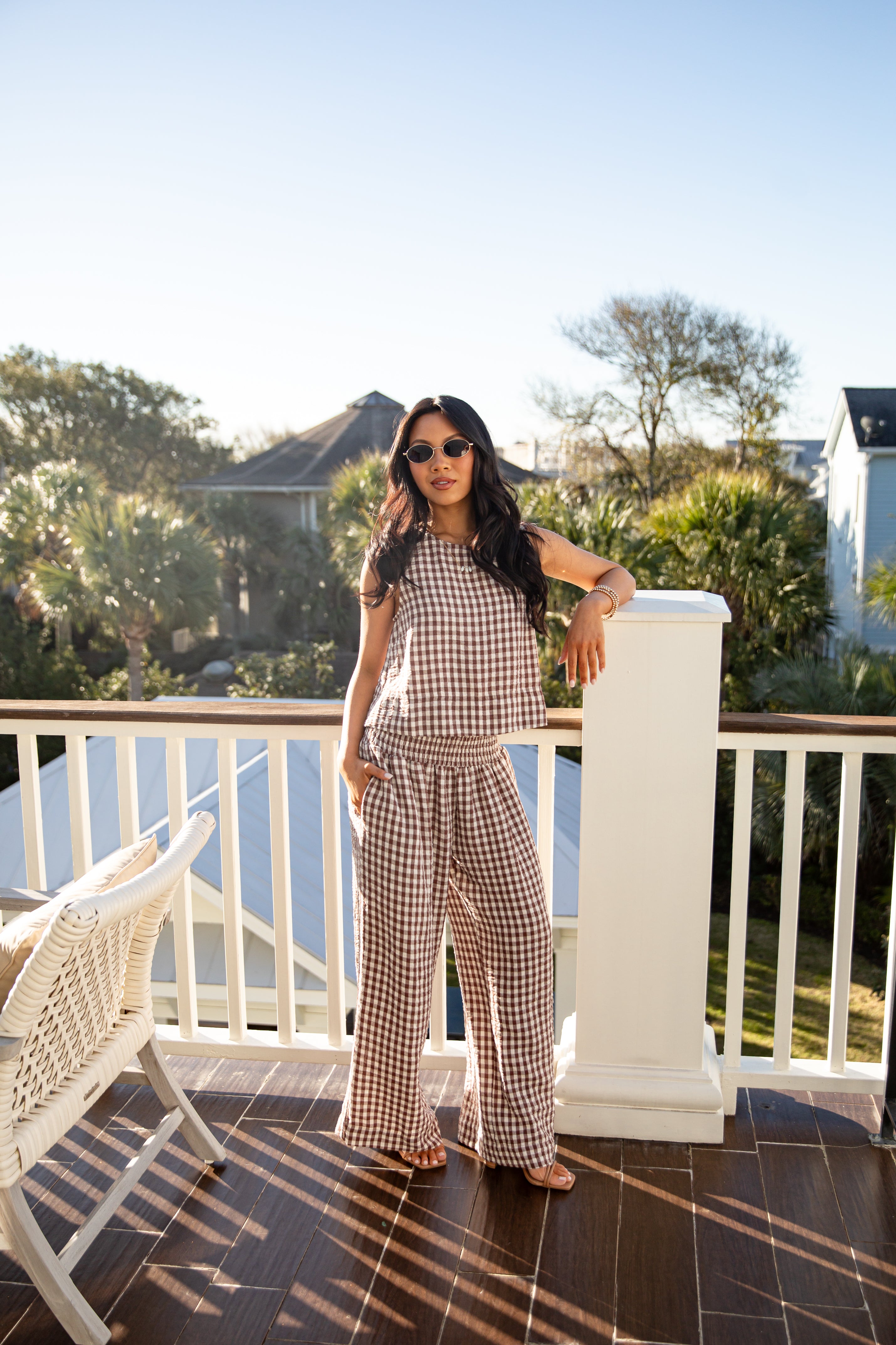 Woman in a checkered outfit standing on a balcony with a scenic background