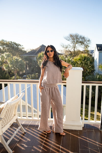 Woman in a checkered outfit standing on a balcony with a scenic background