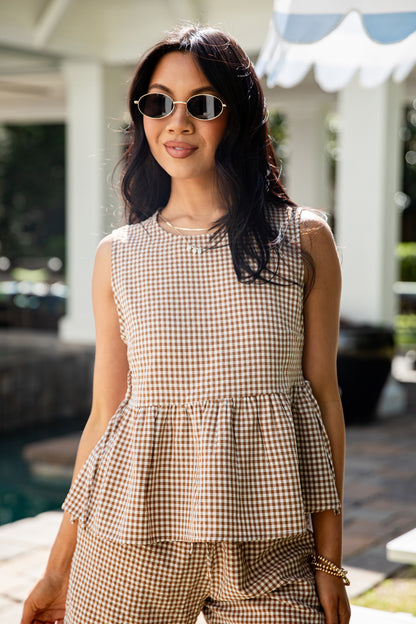 Woman wearing a checkered outfit with sunglasses outdoors.