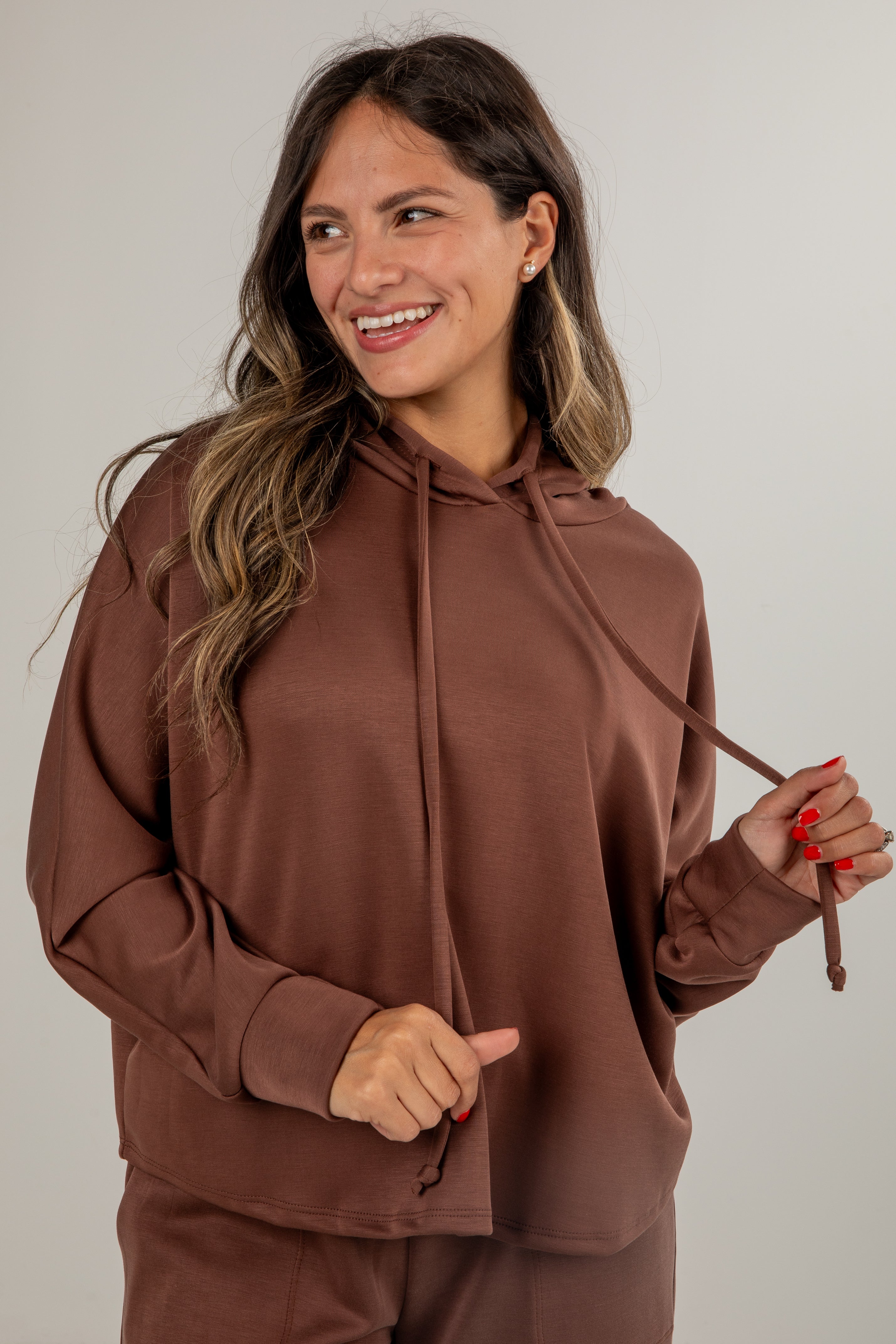 Woman wearing a brown hoodie against a plain background