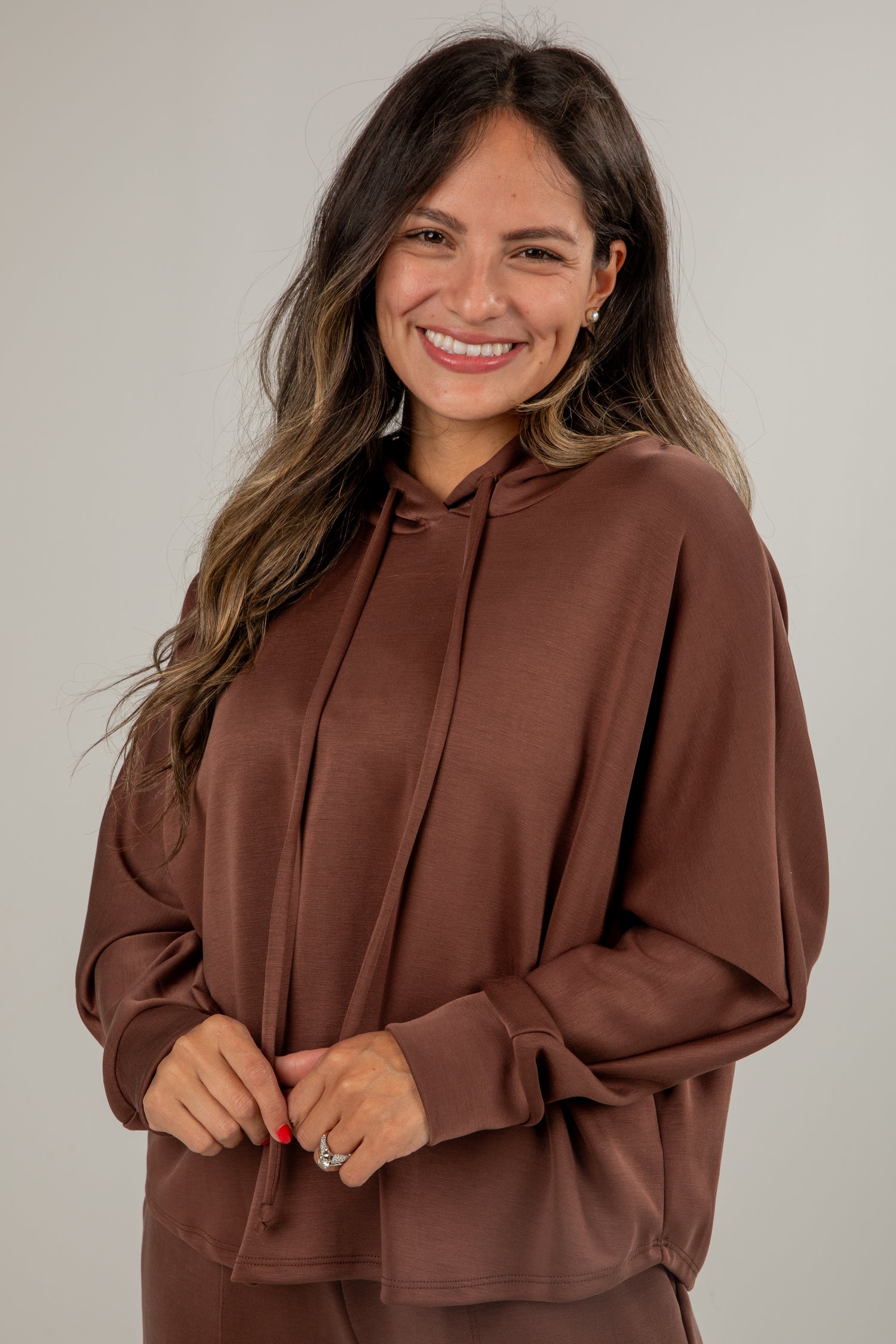 Woman wearing a brown hoodie against a plain background