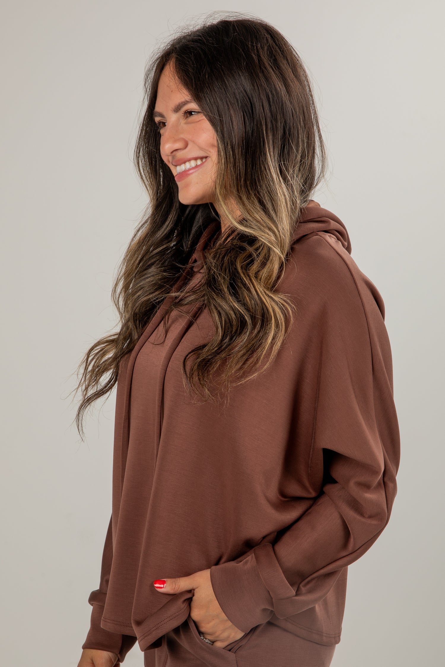 Woman wearing a brown hoodie against a plain background