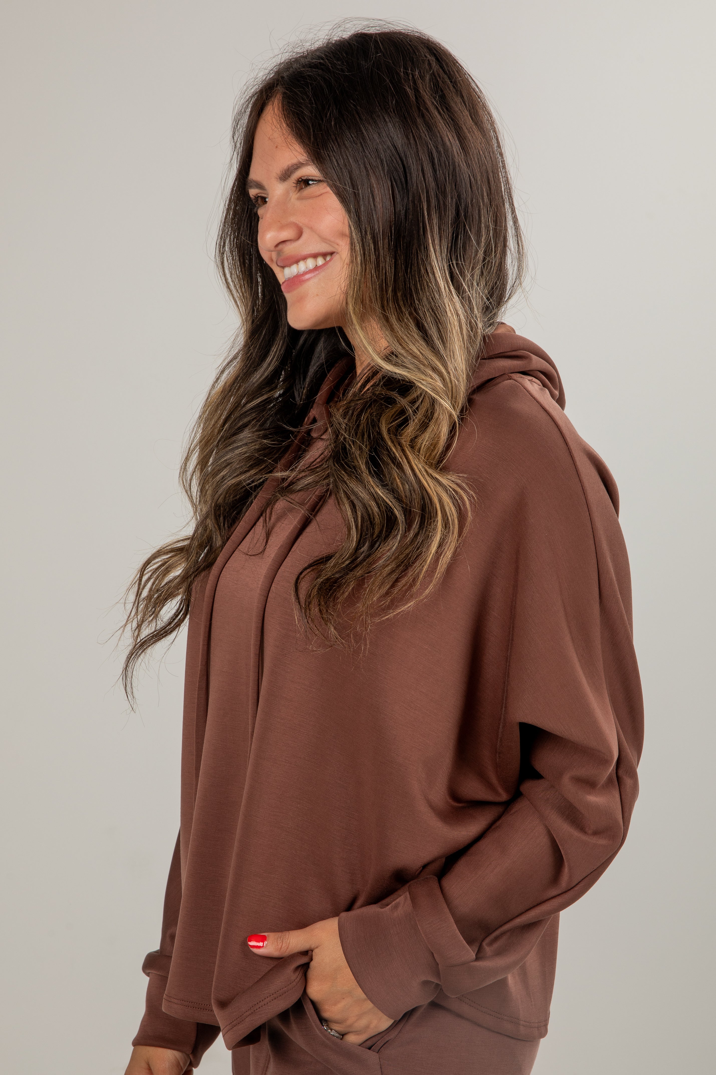 Woman wearing a brown hoodie against a plain background
