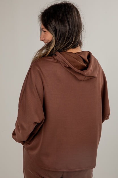 Person wearing a brown hoodie from behind on a plain background