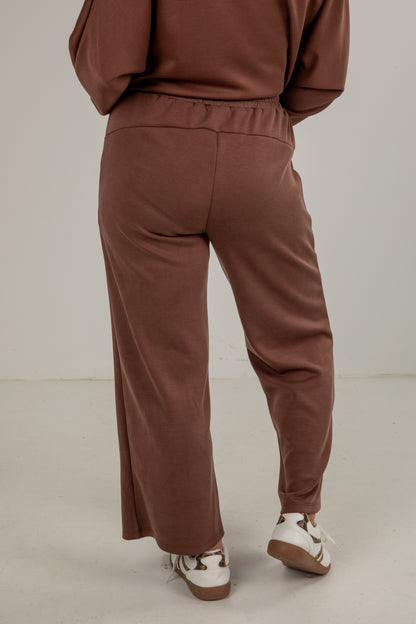 Brown tracksuit worn by a person on a plain background