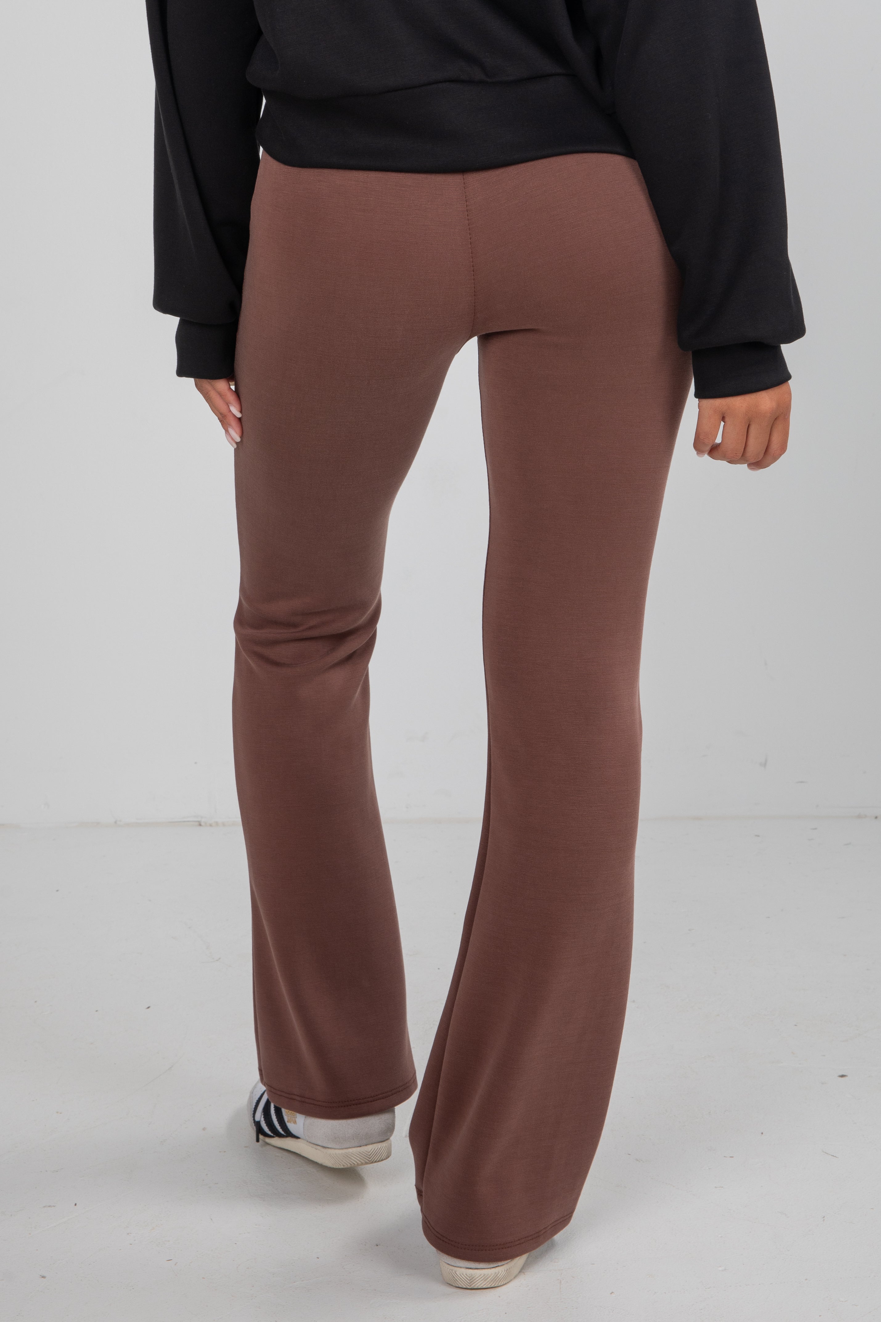 Brown flared pants worn by a person on a white background