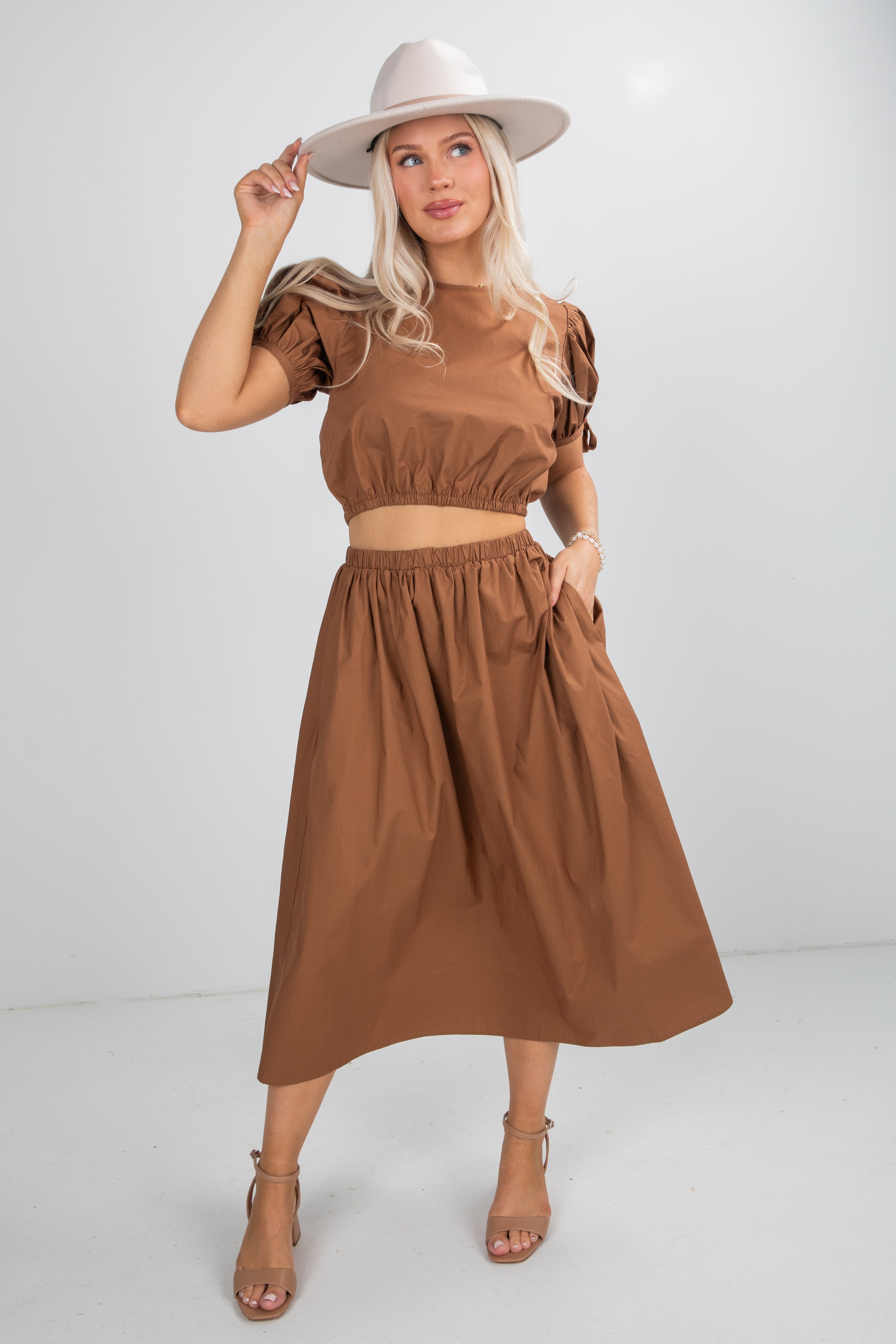Woman wearing a brown dress and hat on a white background