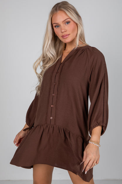 Woman wearing a brown dress against a plain background