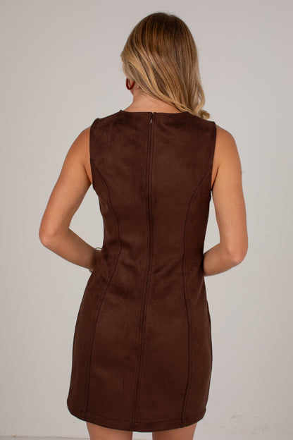 A woman viewed from the back wearing a sleeveless brown faux-suede mini dress with a center back zipper, set against a plain light gray background.