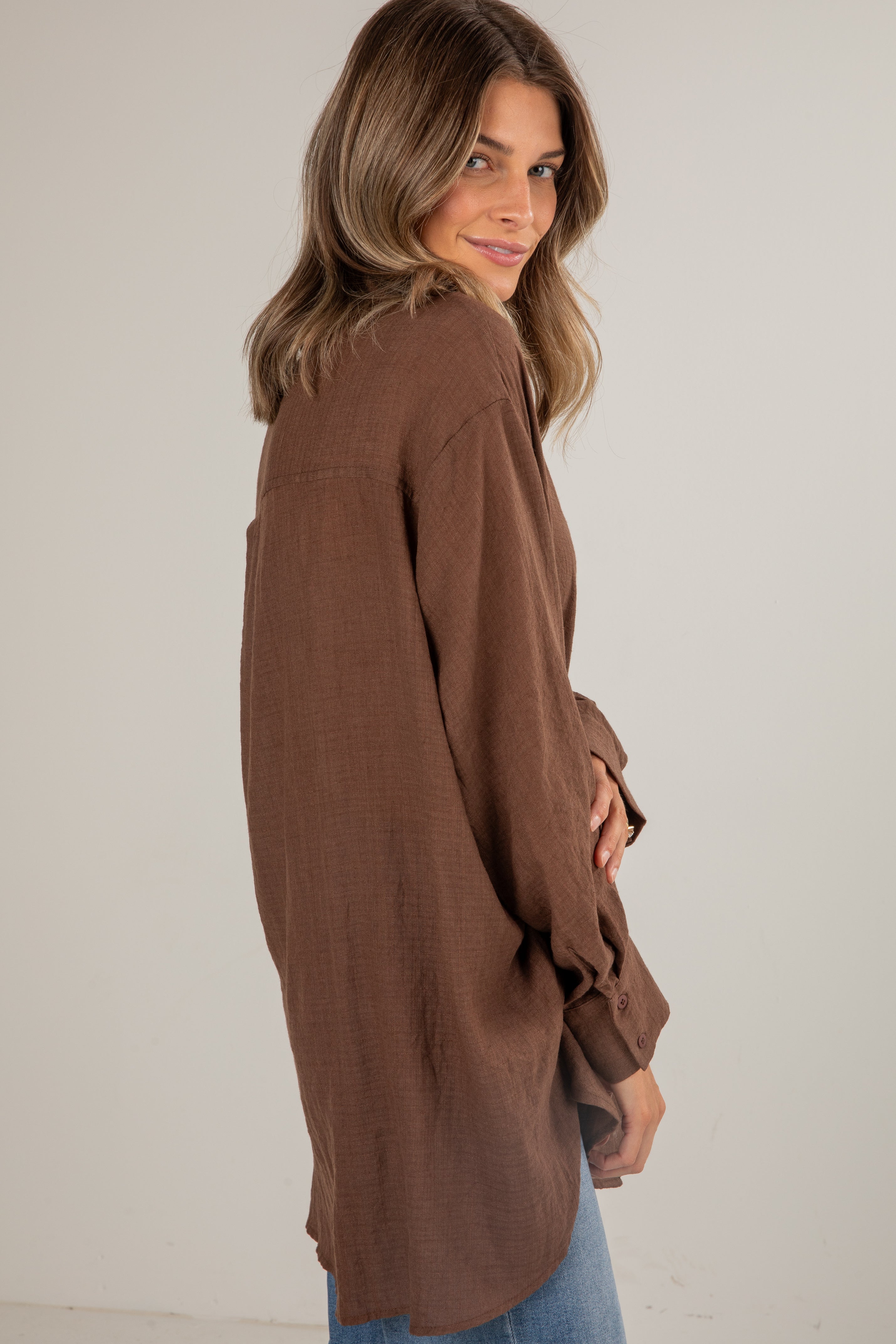 Woman wearing a brown long-sleeve top against a plain background